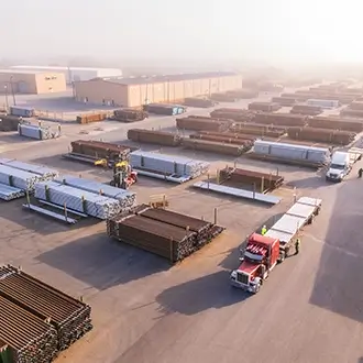 An aerial view of pipes stacked outside of a Workstrings International warehouse