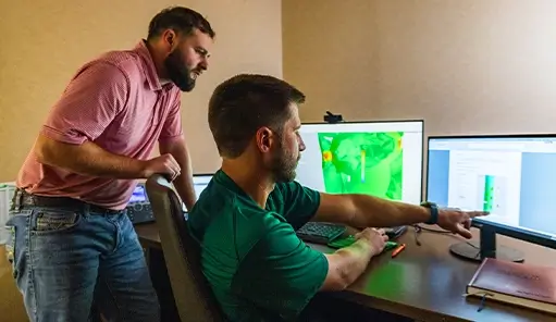 Two Workstrings engineers looking at readouts on a monitor at a desk