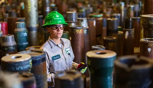 A female Workstrings worker taking inventory of drill pipes